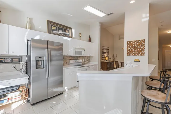 Kitchen with a kitchen bar,  light tile patterned floors, and white cabinetry