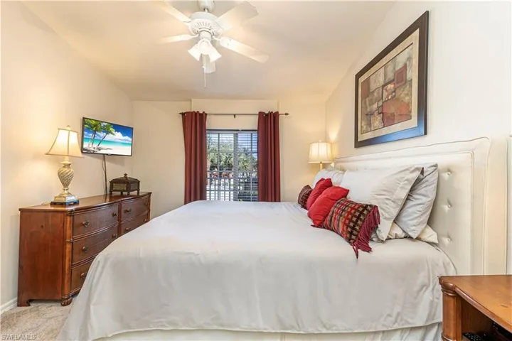 Bedroom featuring light carpet, baseboards, vaulted ceiling, and a ceiling fan