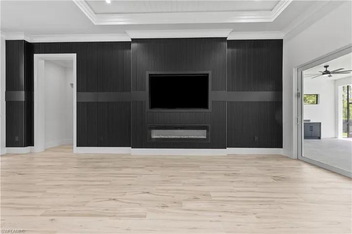 Unfurnished living room with wood finished floors, crown molding, a ceiling fan, and baseboards