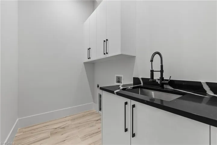 Washroom with cabinet space, light wood-type flooring, electric dryer hookup, baseboards, and hookup for a washing machine