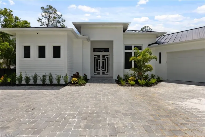 View of front of house featuring a standing seam roof, decorative driveway, a garage, and metal roof