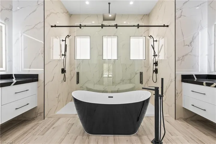 Full bath with vanity, a soaking tub, a marble finish shower, tile walls, and recessed lighting