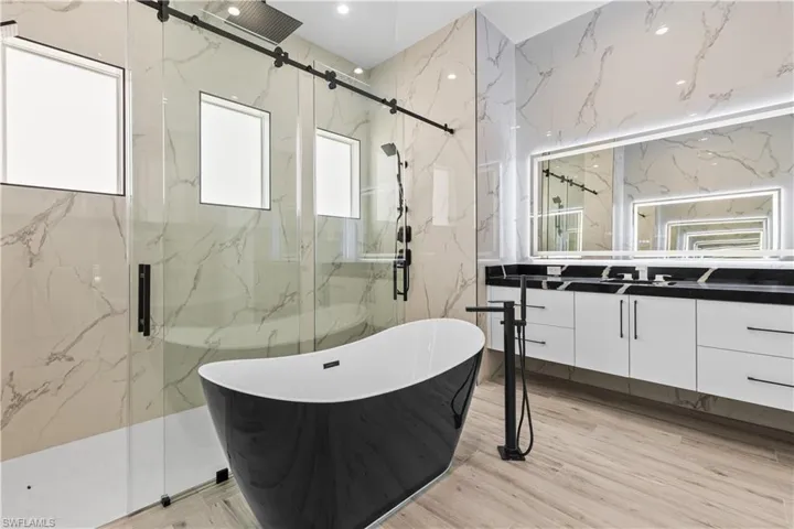 Full bathroom featuring a marble finish shower, vanity, and a soaking tub