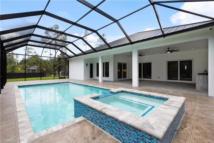 View of pool with ceiling fan, a patio area, a pool with connected hot tub, and a lanai
