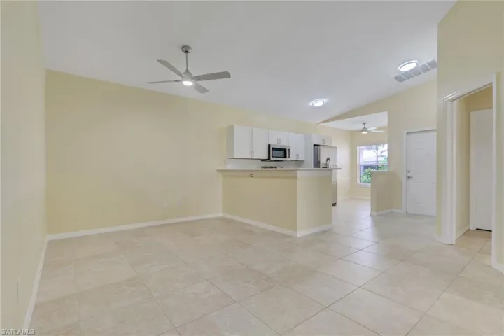 Open-concept living area with large format tile flooring and vaulted ceilings