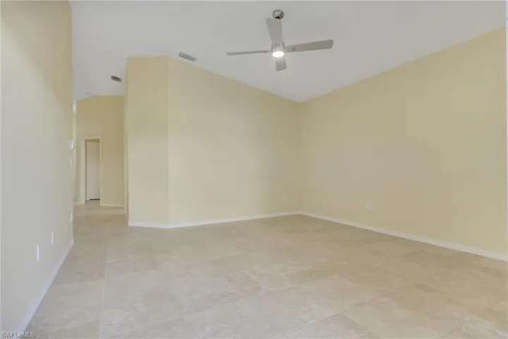Spacious room featuring vaulted ceilings, light-toned walls, and large format tile flooring