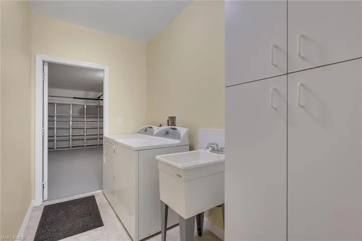 Laundry area featuring a utility sink with a chrome faucet, built-in white cabinetry, and tiled flooring