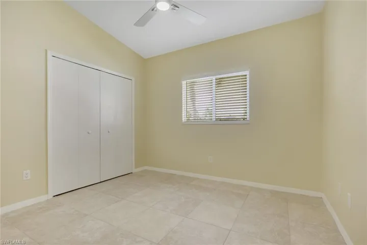 Bedroom featuring neutral-toned walls, tile flooring, a window with horizontal blinds, and a ceiling fan