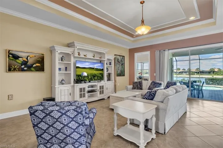 Living room featuring crown molding, a tray ceiling, and light tile patterned floors