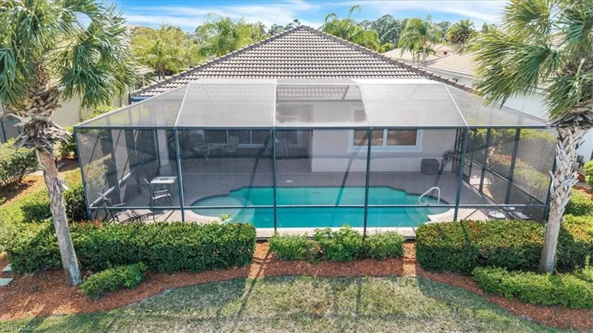 Back of property with an outdoor pool, a sunroom, a lanai, and a tile roof