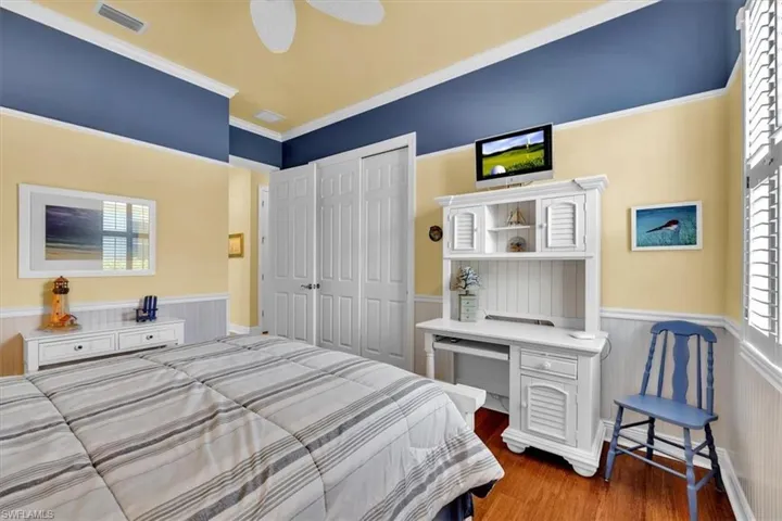 Bedroom with a wainscoted wall, light wood-type flooring, a closet, a ceiling fan, and crown molding