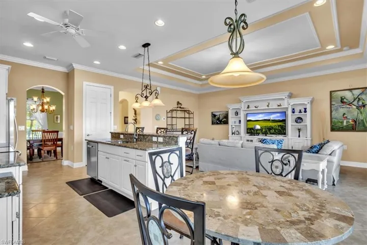 Dining space with ceiling fan, crown molding, light tile patterned floors, suspended lighting, and arched walkways