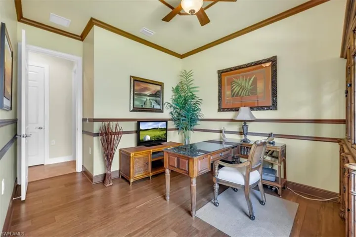 Home office featuring ceiling fan, crown molding, and dark wood-type flooring