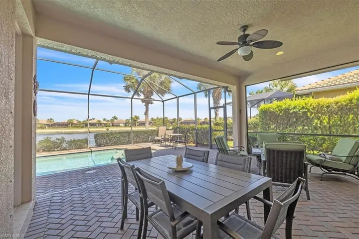View of patio with an outdoor pool, a sunroom, glass enclosure, a ceiling fan, and a water view