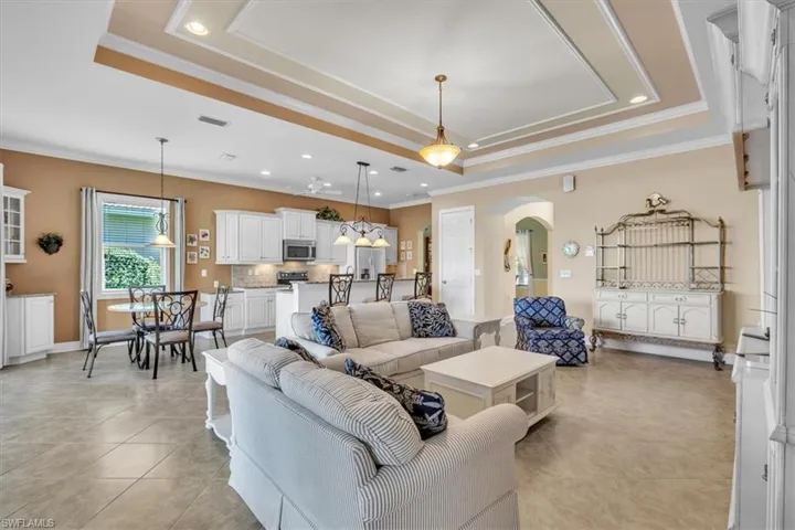 Living room featuring recessed lighting, arched walkways, crown molding, and a tray ceiling