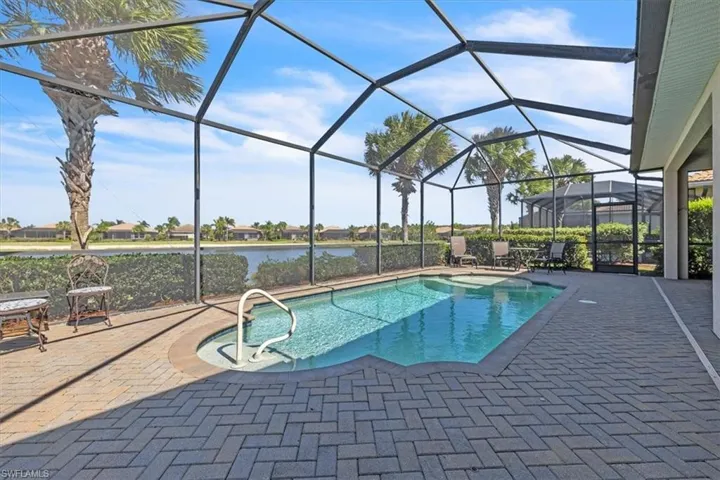 Outdoor pool featuring a sunroom, a patio area, a lanai, and a water view