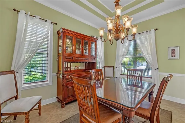 Dining room featuring a raised ceiling, hanging lights, crown molding, and light tile patterned floors