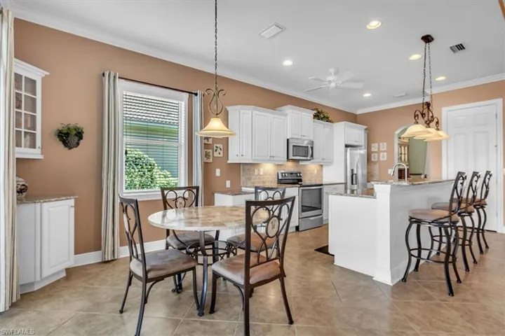 Dining space featuring crown molding, recessed lighting, arched walkways, ceiling fan, and light tile patterned floors