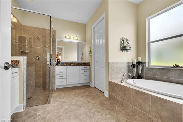Full bath featuring a stall shower, vanity, a bath, and light tile patterned floors