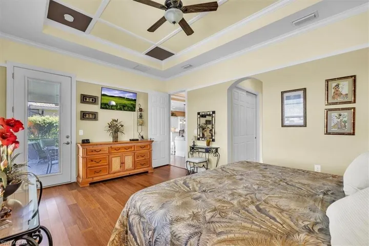 Bedroom featuring hardwood / wood-style floors, access to outside, crown molding, arched walkways, and a ceiling fan