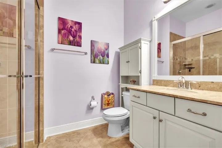 Bathroom featuring vanity, tiled shower, and light tile patterned floors
