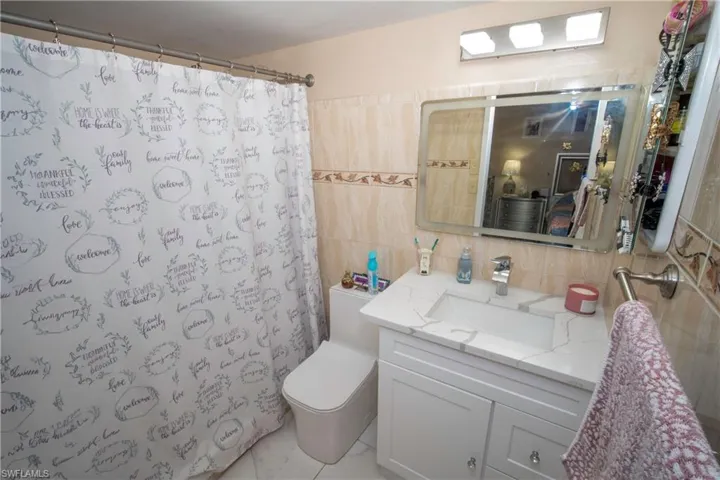 Full bath featuring vanity, tasteful backsplash, a shower with curtain, and tile walls