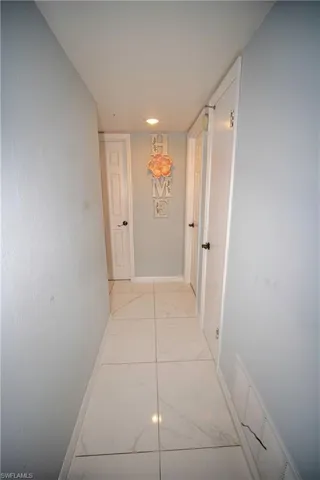 Hallway with light marble finish flooring and baseboards