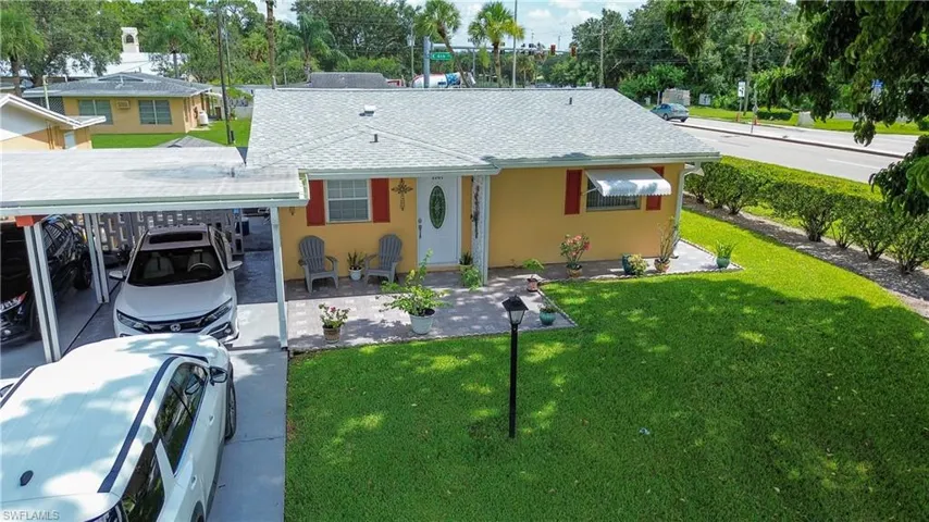 View of front of house with a shingled roof, a front lawn, stucco siding, and a carport