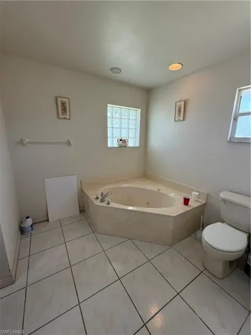 Full bathroom with a tub with jets and light tile patterned flooring