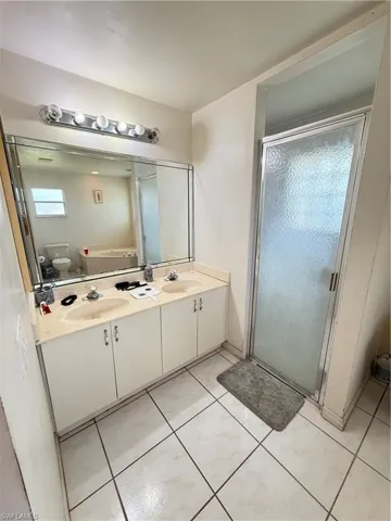 Full bathroom with double vanity and a shower stall