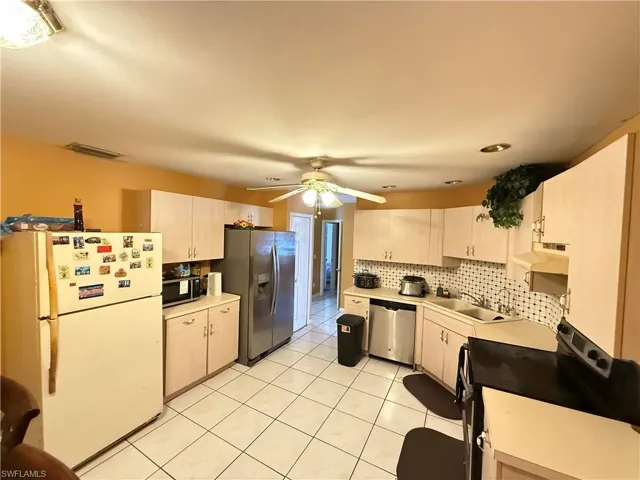 Kitchen with stainless steel appliances, light countertops, light tile patterned floors, and decorative backsplash