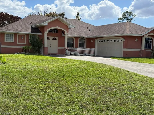 Ranch-style house featuring a front yard, a shingled roof, an attached garage, concrete driveway, and stucco siding