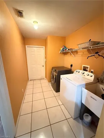 Laundry area with light tile patterned floors and independent washer and dryer