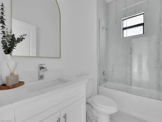 Full bathroom featuring enclosed tub / shower combo, tile flooring, vanity, and toilet