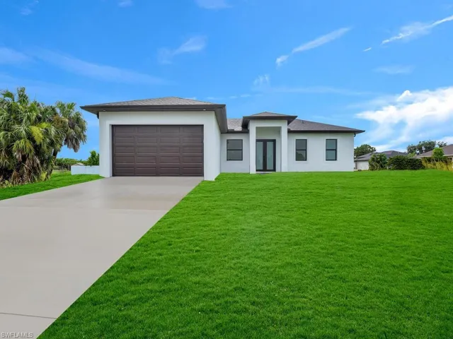View of front facade featuring a front yard and a garage