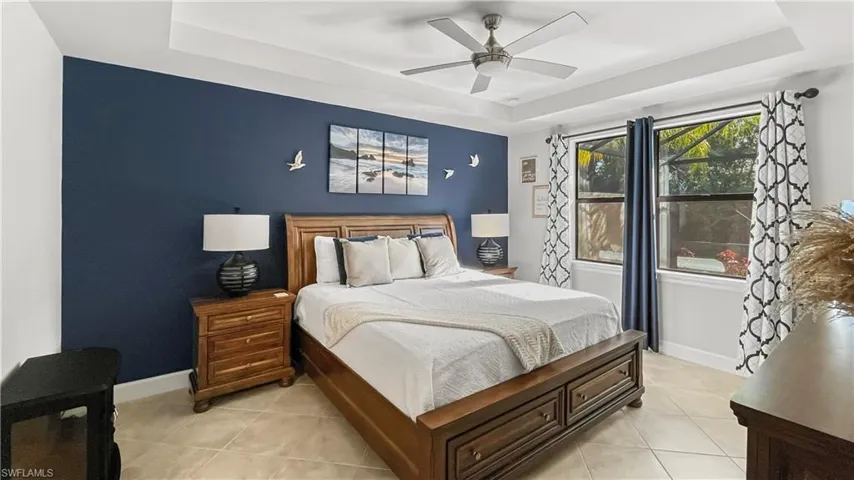 Tiled bedroom with a tray ceiling and ceiling fan
