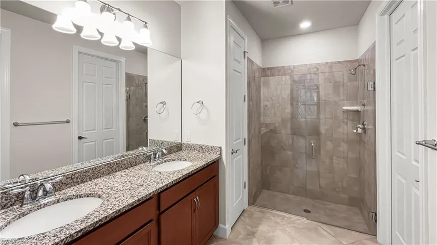 Bathroom featuring tile patterned flooring, walk in shower, and vanity