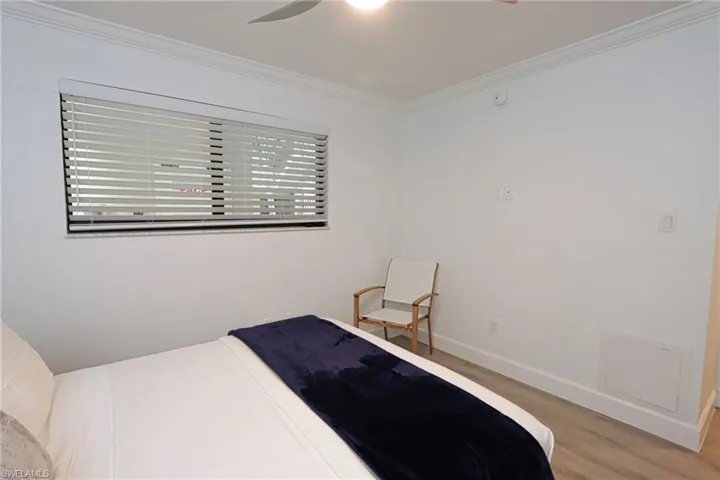 Bedroom with wood finished floors, ornamental molding, baseboards, and a ceiling fan