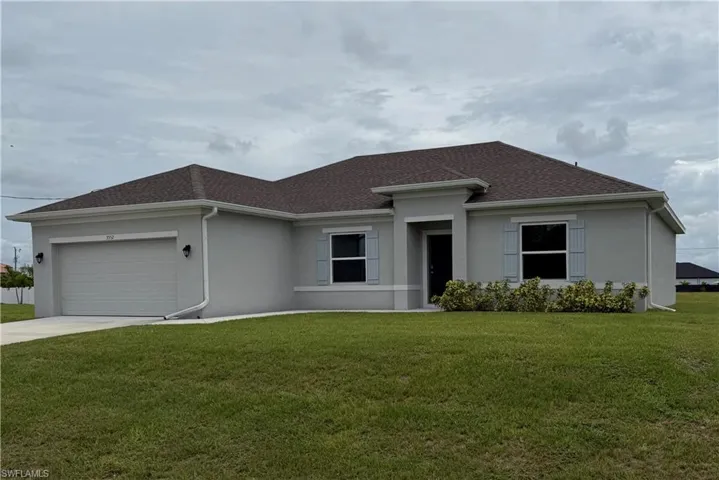 View of front of house featuring stucco siding, an attached garage, concrete driveway, and a front yard