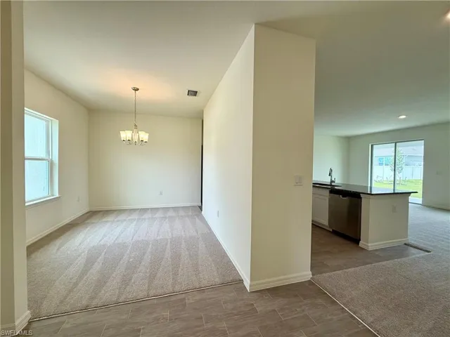 Unfurnished dining area featuring light colored carpet and a chandelier