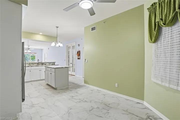Kitchen with light marble finish floors, light stone counters, a chandelier, hanging light fixtures, and ceiling fan