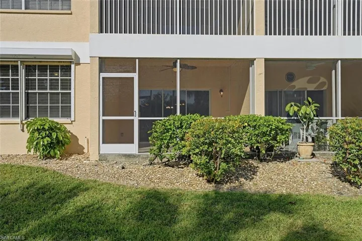 Doorway to property featuring a sunroom, stucco siding, and a yard
