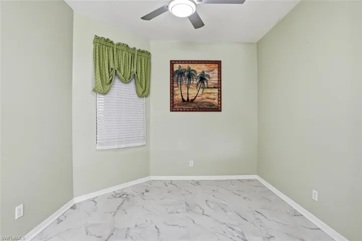 Unfurnished room featuring light marble finish flooring and baseboards