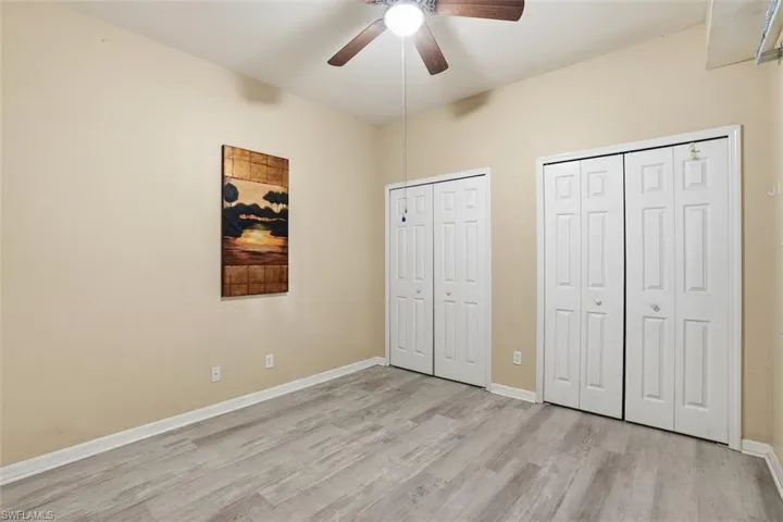 Unfurnished bedroom with multiple closets, a ceiling fan, and light wood-style flooring