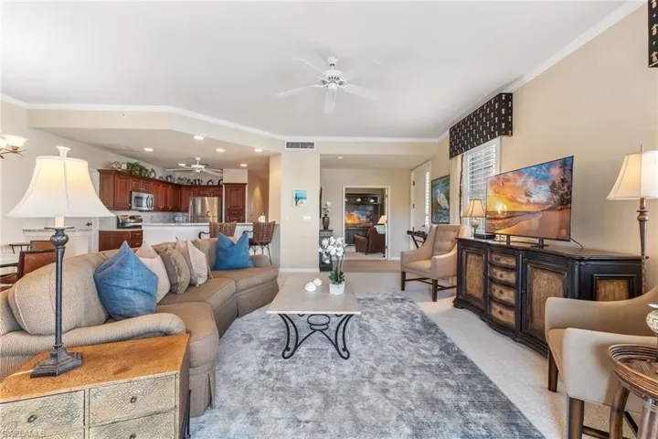 Living room featuring ceiling fan, ornamental molding, visible vents, and light colored carpet