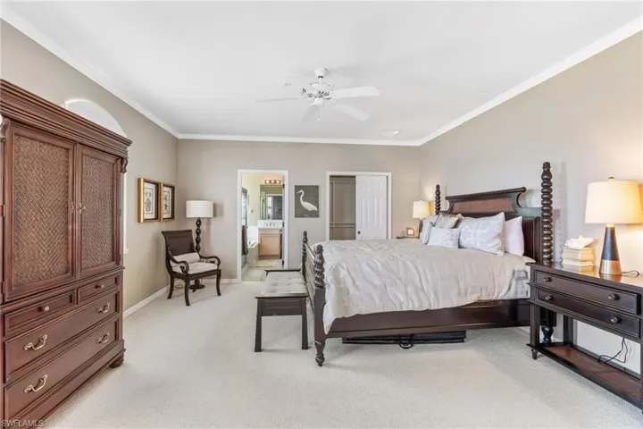 Bedroom featuring baseboards, ornamental molding, connected bathroom, and light colored carpet