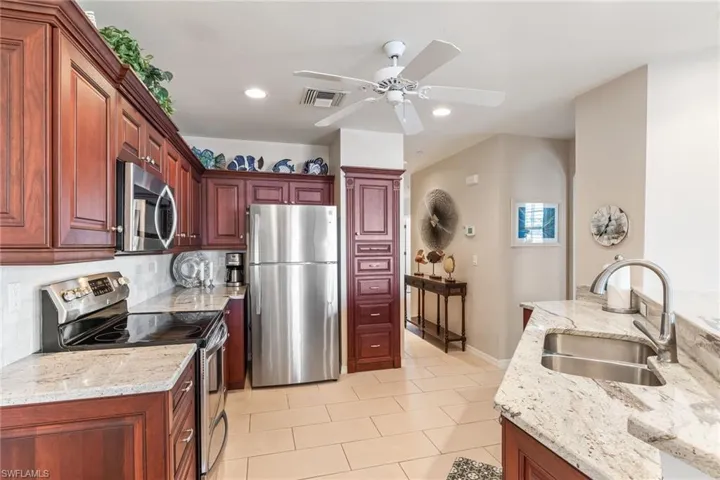 Kitchen with tasteful backsplash, visible vents, stainless steel appliances, dark brown cabinets, and a sink