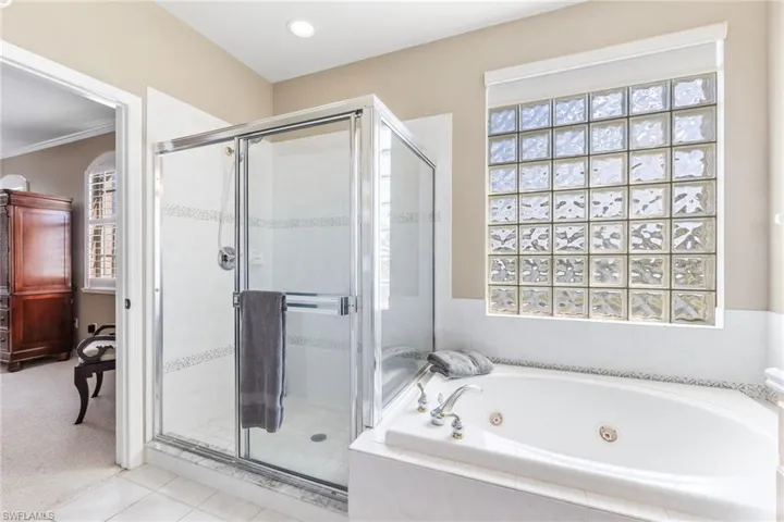 Full bath featuring a whirlpool tub, tile patterned flooring, a shower stall, and crown molding