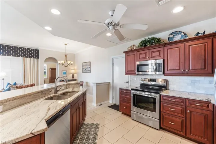 Kitchen with stainless steel appliances, a sink, backsplash, and dark brown cabinets