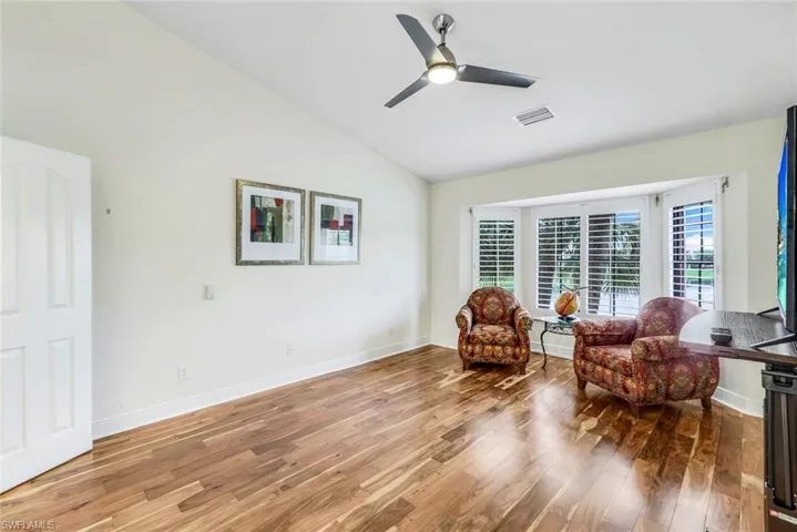 Primary bedroom featuring ceiling fan, high vaulted ceiling, and Acacia wood floors